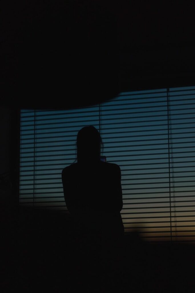 a silhouette of a person sitting in front of a window